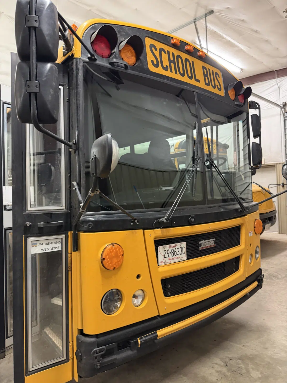 Yellow school bus with new windshield inside a garage — A+ Glass LLC in Billings