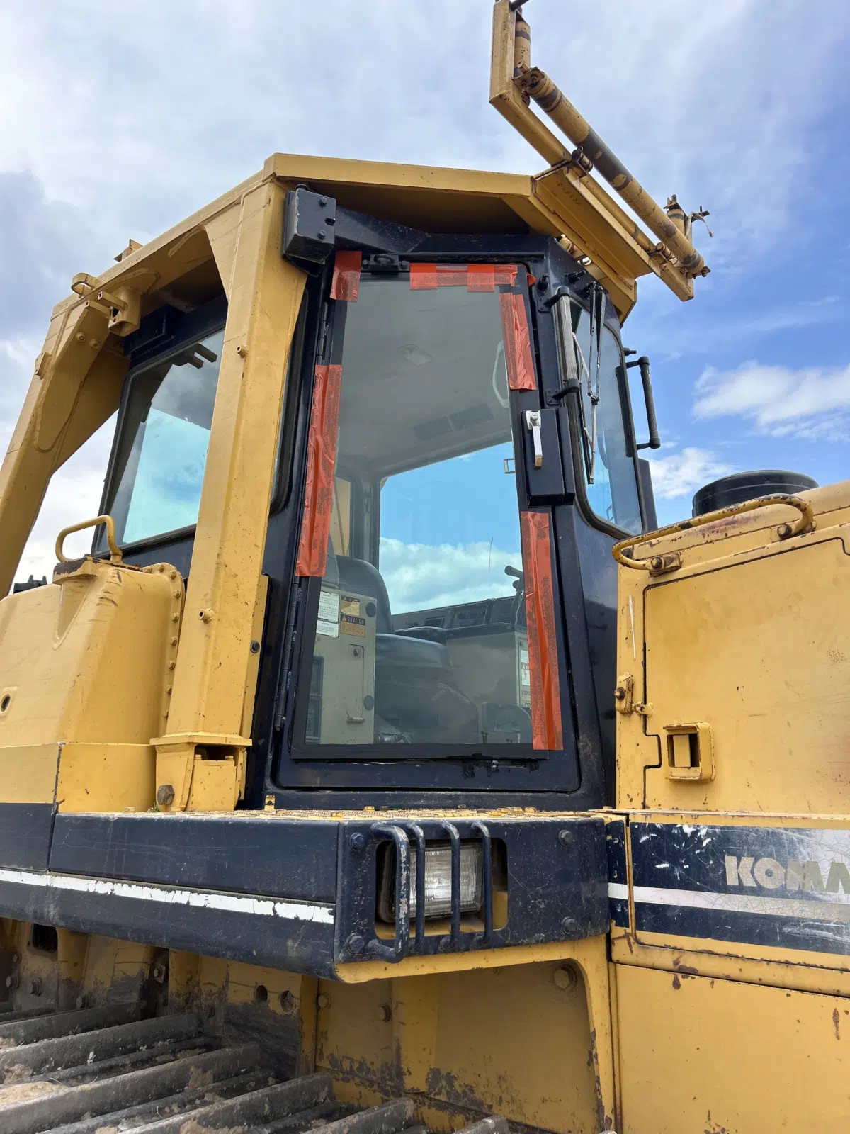 Taped heavy equipment cab door glass on a Komatsu dozer — A+ Glass LLC in Billings
